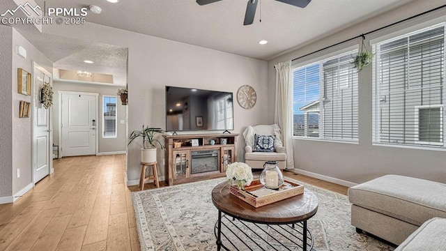 living room with ceiling fan, light hardwood / wood-style floors, and a textured ceiling