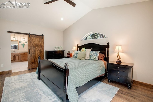 bedroom featuring light wood-type flooring, ensuite bathroom, ceiling fan, a barn door, and lofted ceiling