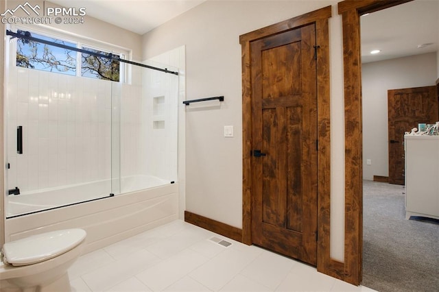 bathroom with toilet and bath / shower combo with glass door