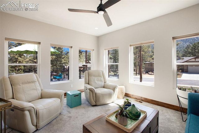 living area with light carpet and ceiling fan