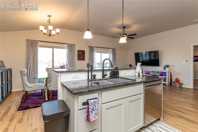 kitchen with white cabinetry, sink, hanging light fixtures, light hardwood / wood-style flooring, and dark stone countertops