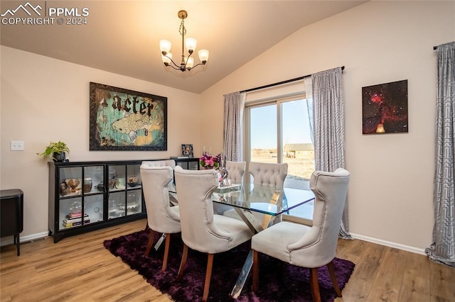 dining space featuring hardwood / wood-style flooring, vaulted ceiling, and an inviting chandelier