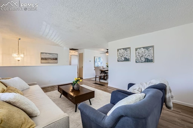 living room with ceiling fan with notable chandelier, wood-type flooring, and a textured ceiling