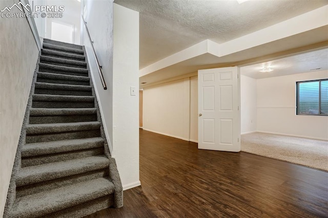 staircase with hardwood / wood-style floors and a textured ceiling