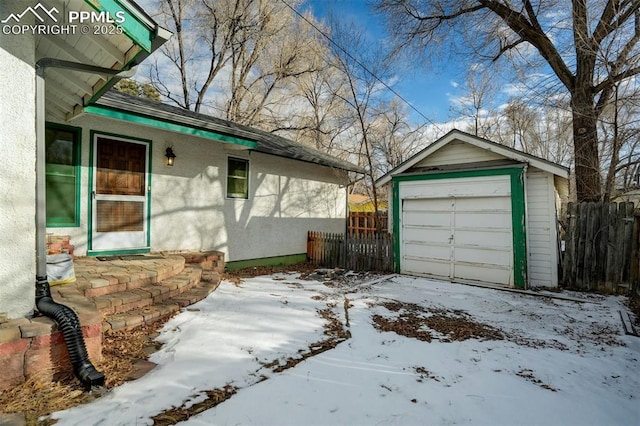 view of snow covered exterior featuring a garage and an outbuilding