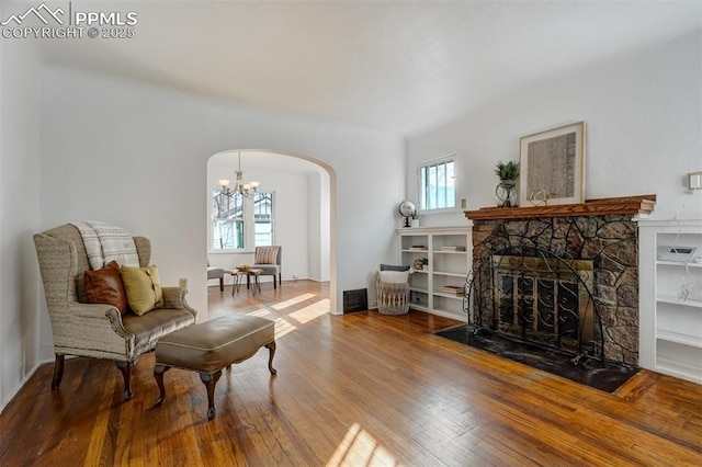 sitting room with an inviting chandelier, a healthy amount of sunlight, hardwood / wood-style floors, and a fireplace