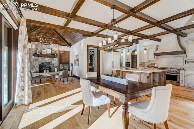 dining room with beam ceiling, light wood-type flooring, a fireplace, and an inviting chandelier