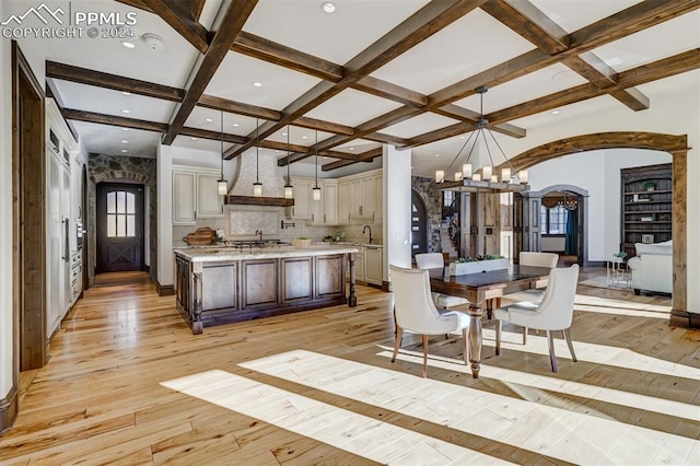 kitchen featuring backsplash, light wood-type flooring, decorative light fixtures, a kitchen island, and a breakfast bar area