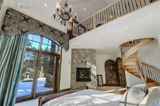 bedroom featuring access to exterior, a large fireplace, a towering ceiling, and a chandelier