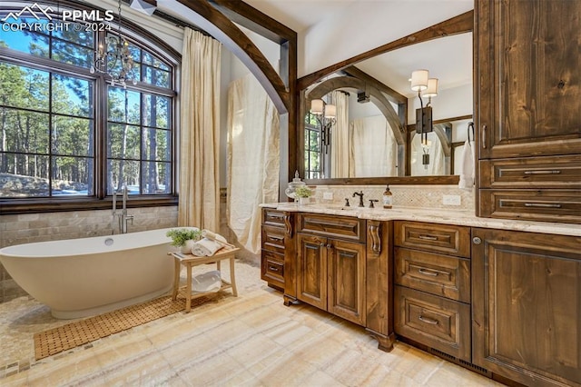 bathroom featuring a washtub, vanity, a chandelier, and plenty of natural light