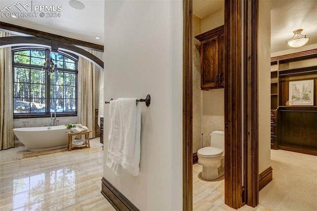 bathroom with toilet, a bathtub, and a notable chandelier