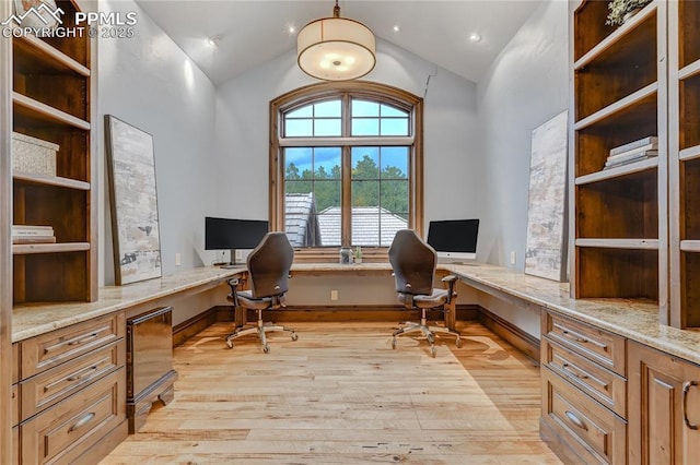 office featuring built in desk, light hardwood / wood-style floors, and lofted ceiling