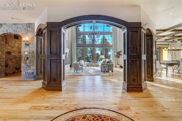 entryway featuring beam ceiling, a notable chandelier, and light wood-type flooring