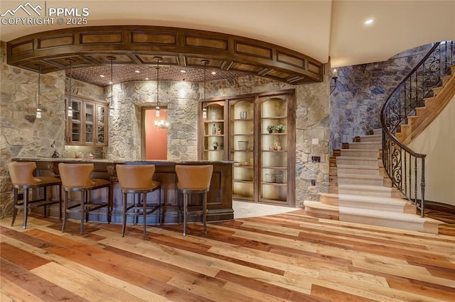 bar with light wood-type flooring and hanging light fixtures