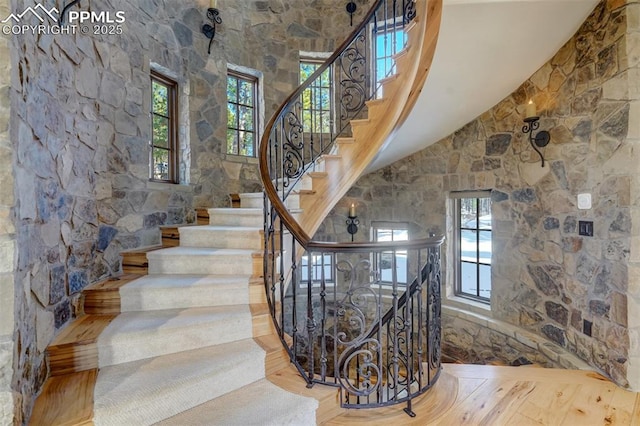 stairway featuring high vaulted ceiling and a wealth of natural light