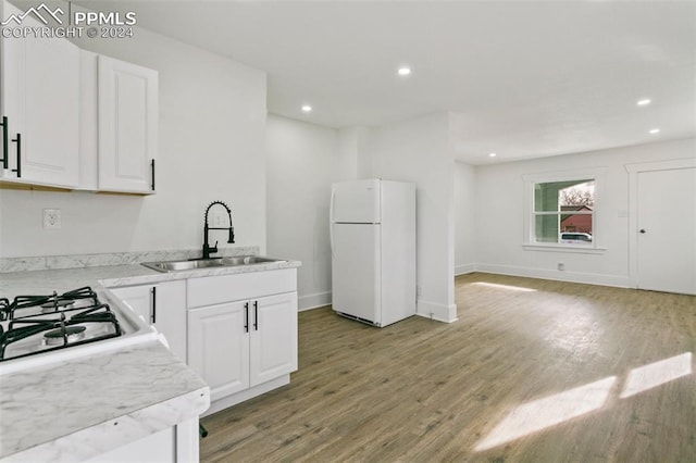 kitchen featuring white refrigerator, light hardwood / wood-style flooring, white cabinetry, and sink