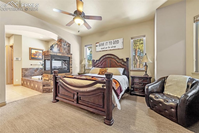 bedroom featuring ceiling fan, a fireplace, and light carpet