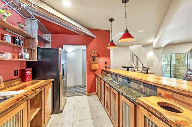 kitchen with stainless steel fridge with ice dispenser, hanging light fixtures, butcher block counters, and light tile patterned flooring