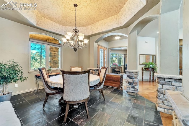 dining area with an inviting chandelier, a raised ceiling, and plenty of natural light