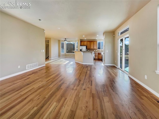 unfurnished living room with light wood-type flooring and ceiling fan