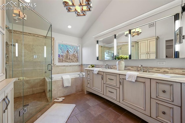 bathroom with a notable chandelier, vanity, lofted ceiling, and shower with separate bathtub