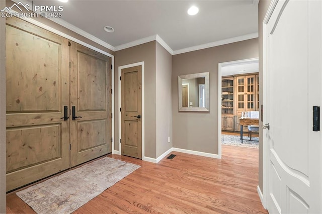 foyer with light hardwood / wood-style flooring and crown molding