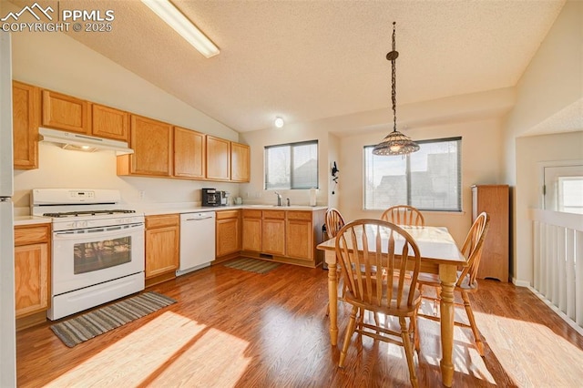 kitchen featuring pendant lighting, white appliances, sink, vaulted ceiling, and light wood-type flooring