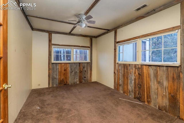 spare room with ceiling fan, wooden walls, and carpet floors