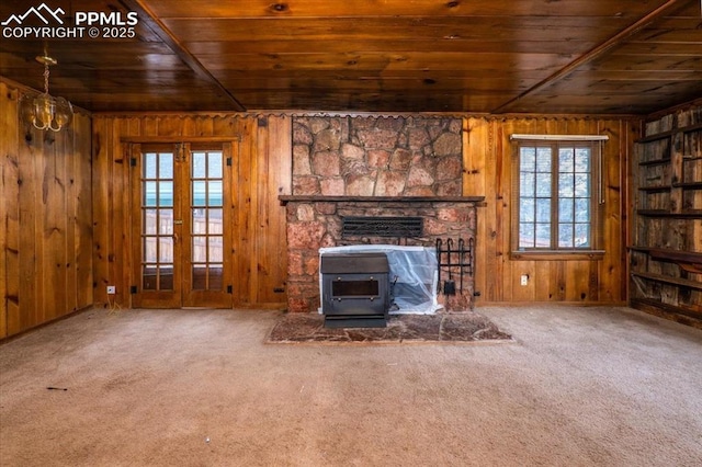 unfurnished living room featuring carpet flooring, wooden ceiling, french doors, and a wood stove