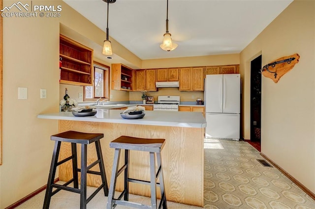 kitchen featuring kitchen peninsula, a kitchen bar, white appliances, sink, and decorative light fixtures