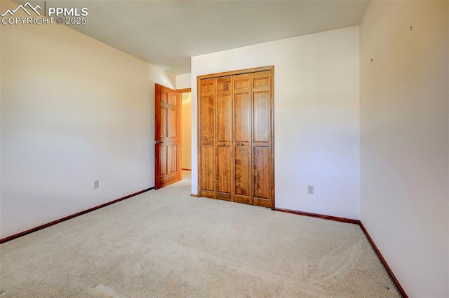 unfurnished bedroom with a closet and light colored carpet