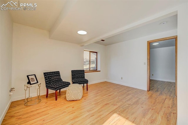 sitting room with beam ceiling and light wood-type flooring