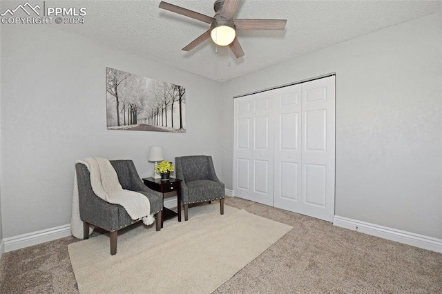 living area featuring a textured ceiling, carpet flooring, and ceiling fan