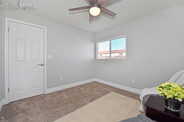 sitting room featuring ceiling fan, carpet flooring, and a textured ceiling