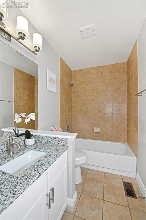 full bathroom with vanity, tiled shower / bath, toilet, and tile patterned floors