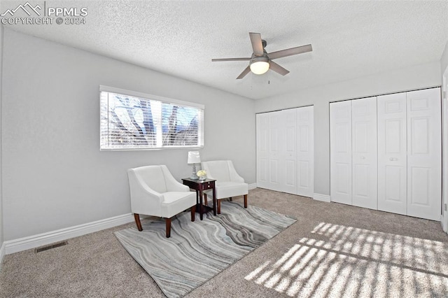 sitting room with carpet floors, a textured ceiling, and ceiling fan