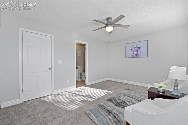 sitting room with ceiling fan, carpet, and a textured ceiling