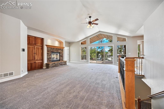 unfurnished living room featuring a stone fireplace, vaulted ceiling, ceiling fan, and carpet