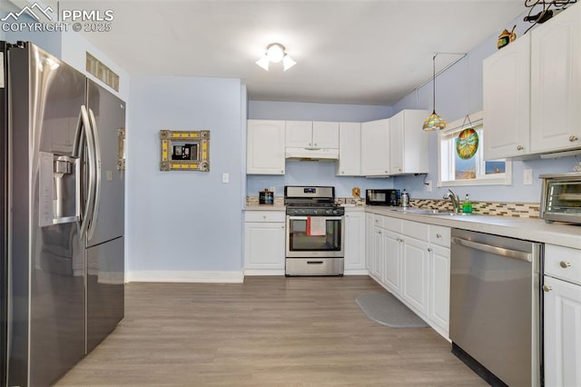 kitchen featuring pendant lighting, appliances with stainless steel finishes, white cabinetry, sink, and light wood-type flooring