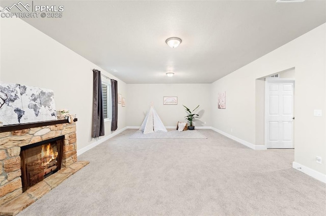 interior space with light colored carpet and a stone fireplace