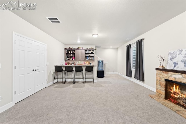 bar featuring a fireplace and light colored carpet