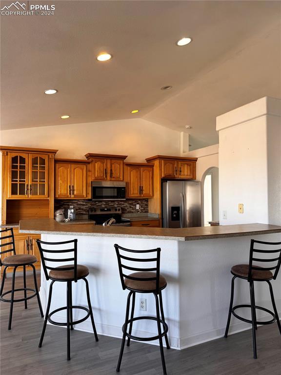 kitchen featuring a breakfast bar, appliances with stainless steel finishes, and lofted ceiling