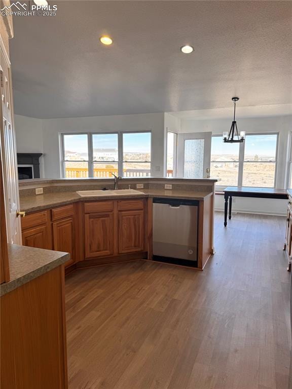 kitchen featuring stainless steel dishwasher, sink, an inviting chandelier, hardwood / wood-style floors, and hanging light fixtures