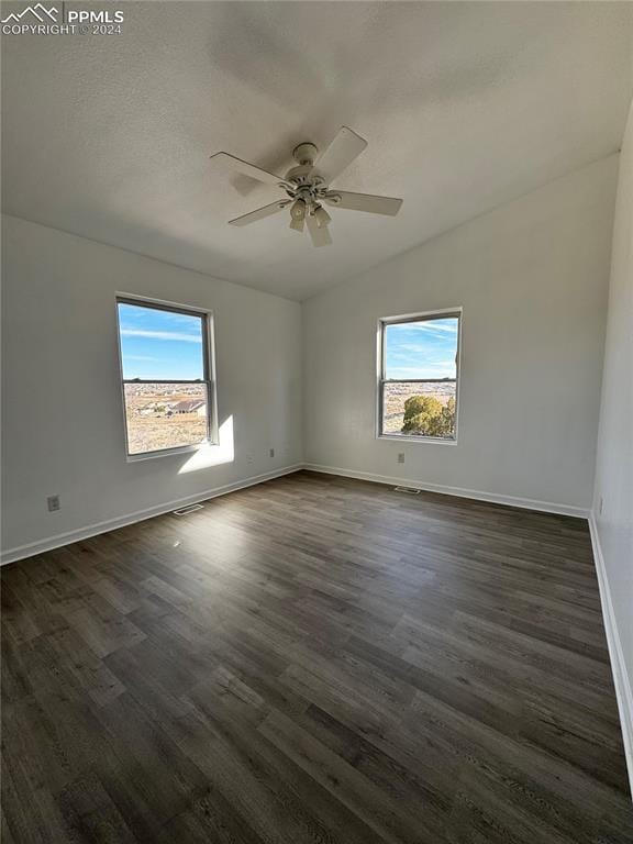 unfurnished room featuring a wealth of natural light, dark hardwood / wood-style flooring, and ceiling fan