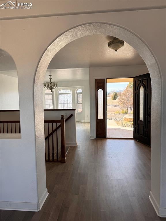 entryway with dark wood-type flooring and an inviting chandelier