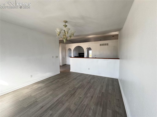 unfurnished living room featuring dark wood-type flooring and an inviting chandelier