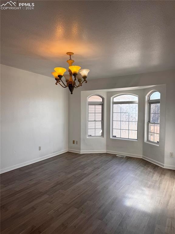 unfurnished room with a chandelier, dark hardwood / wood-style floors, and a wealth of natural light