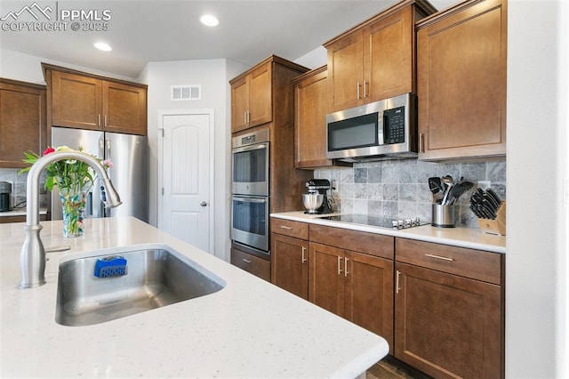 kitchen featuring decorative backsplash, sink, light stone countertops, and stainless steel appliances