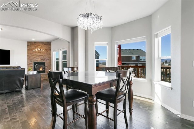 dining area featuring a fireplace, dark hardwood / wood-style floors, and a notable chandelier