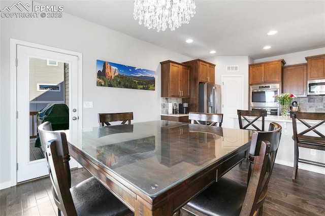 dining room with dark hardwood / wood-style floors and an inviting chandelier